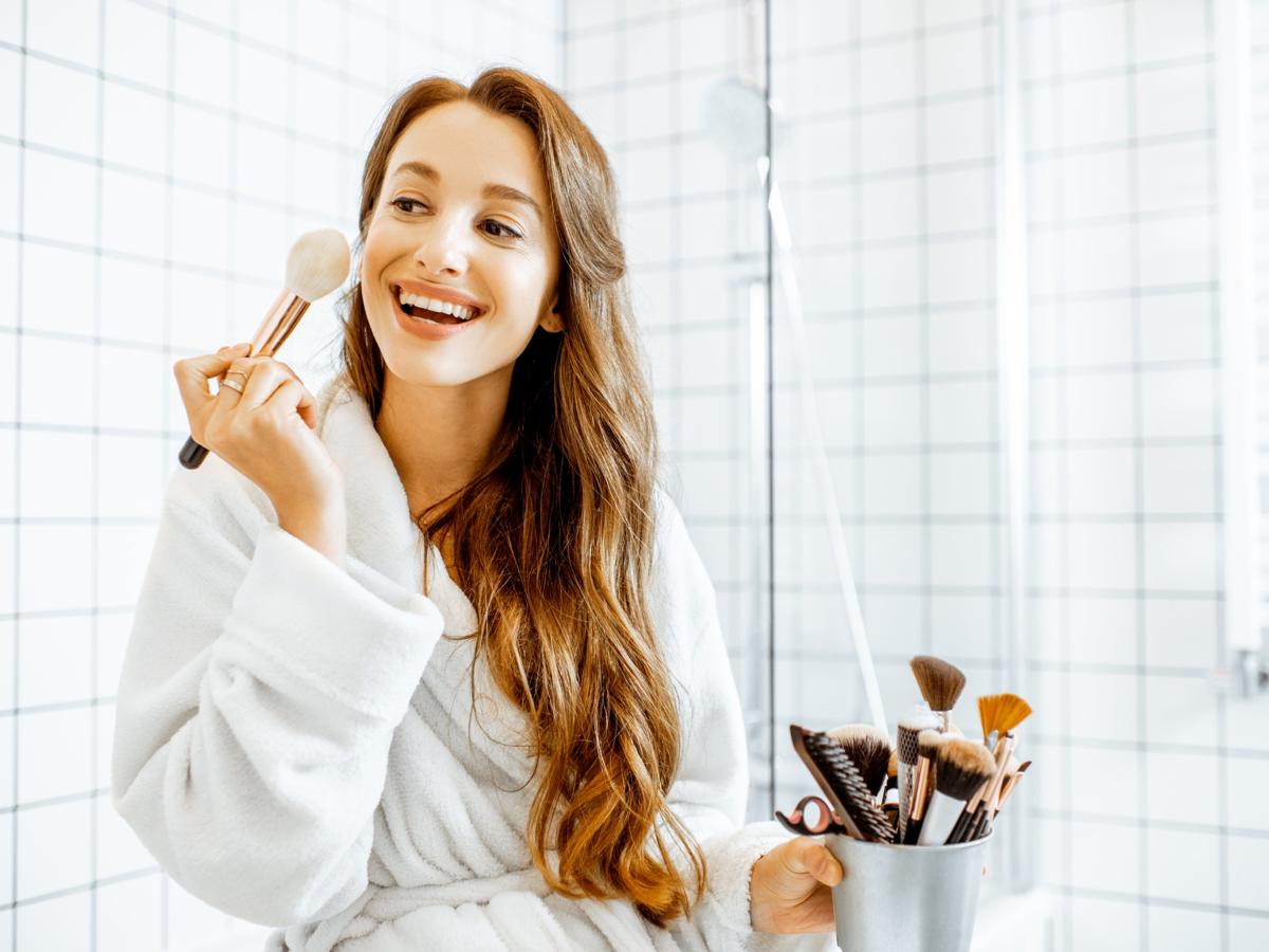 Woman applying cosmetics in bathroom